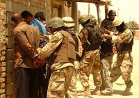 Iraqi soldiers searching detainees at Abu Ghraib